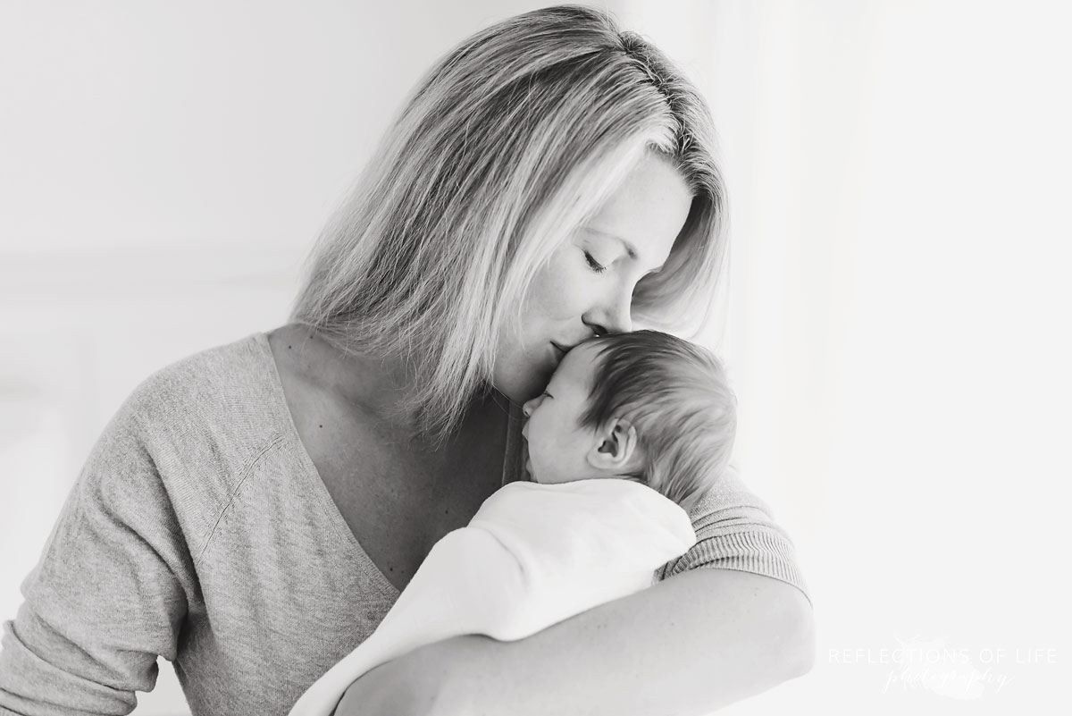 025 Black and white image of mom kissing newborn baby boy in Niagara Region of Ontario.jpg