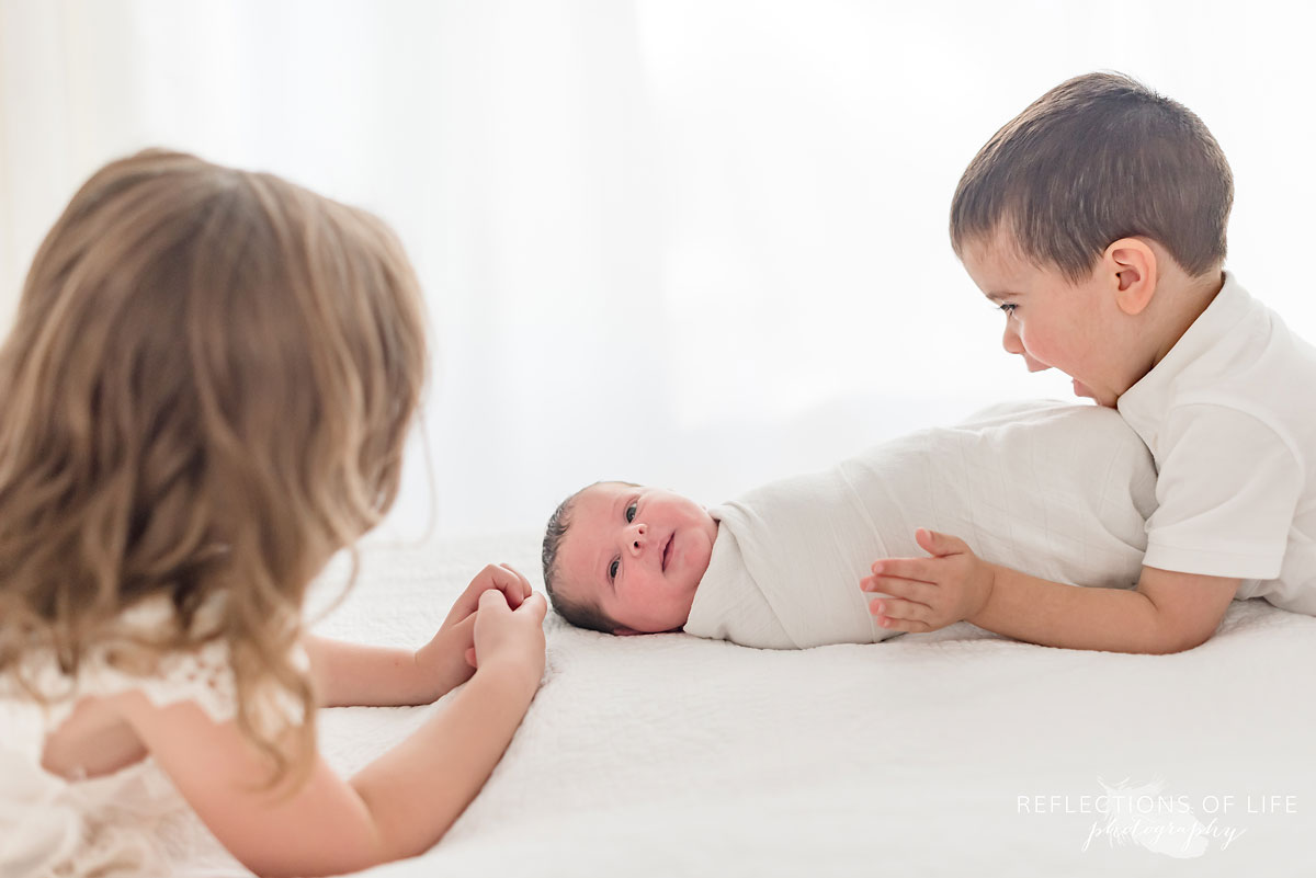 Siblings looking down at new baby sister