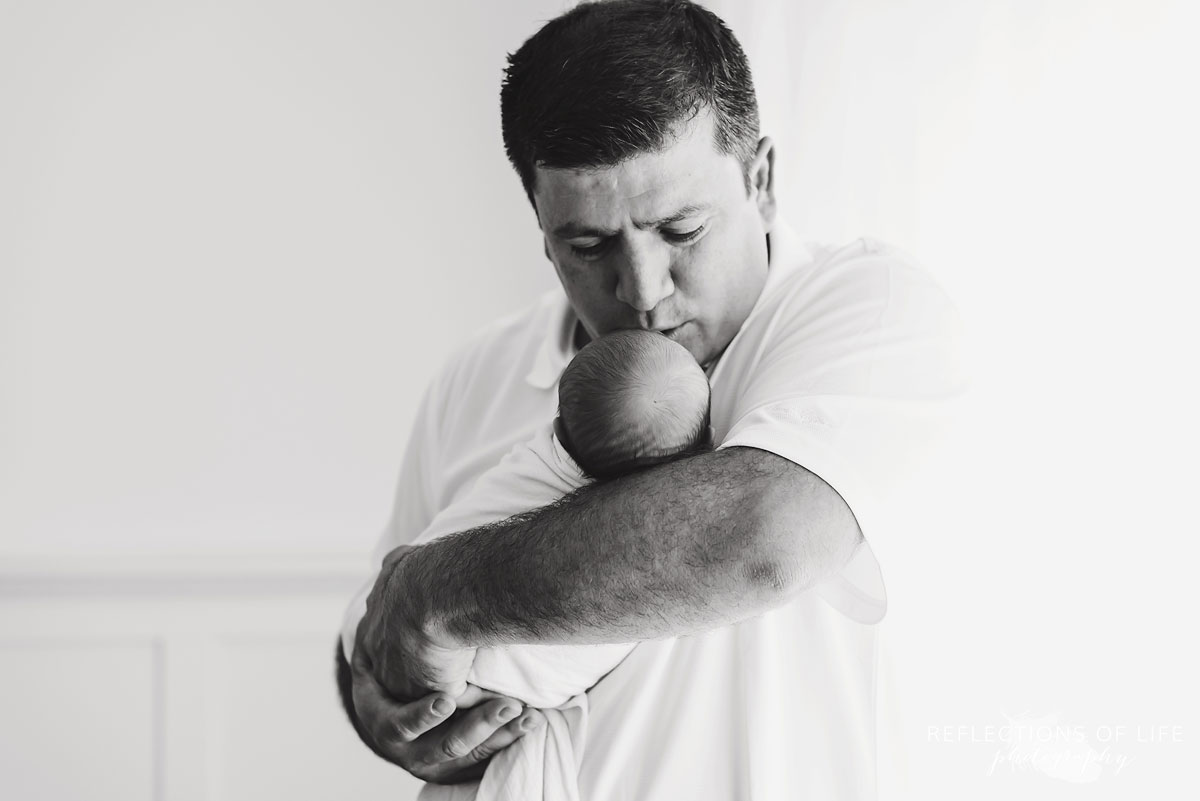 Dad holding his newborn baby boy and giving him a kiss