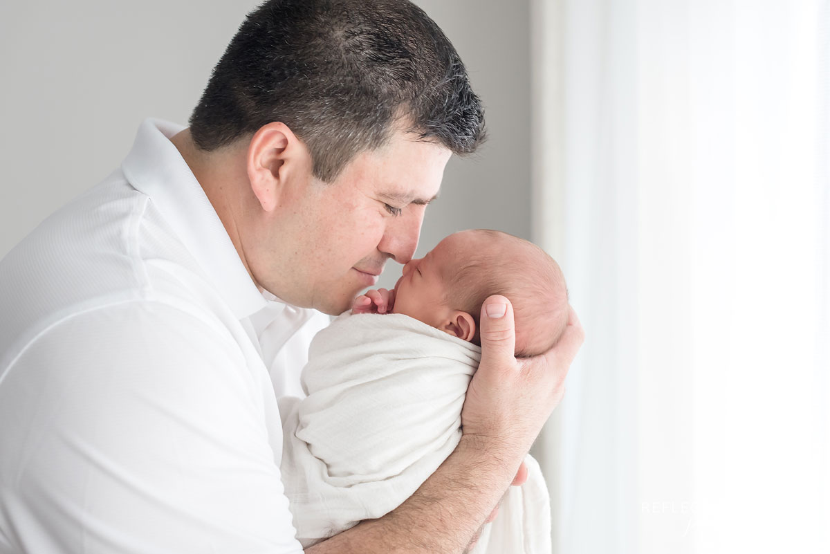 Dad kissing little newborn baby boy Jaxon