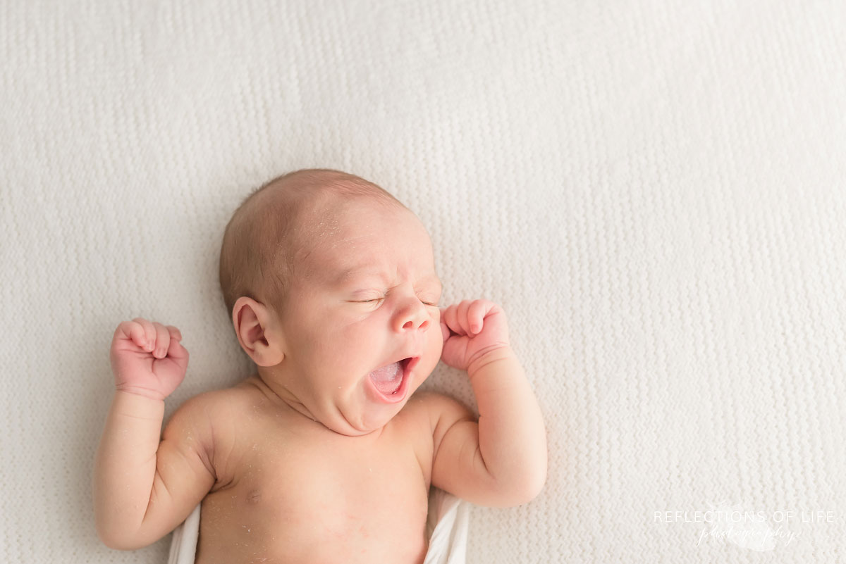 Newborn baby boy yawning and stretching