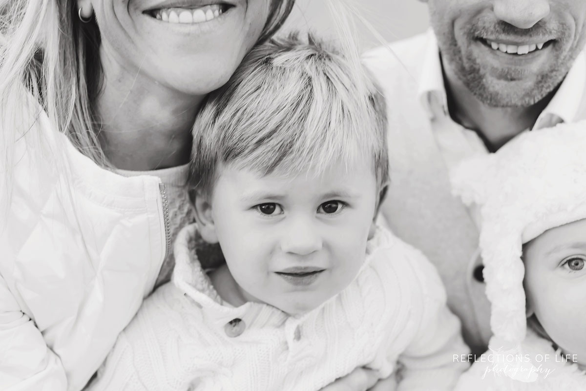 black and white photo of little boy smiling with his family