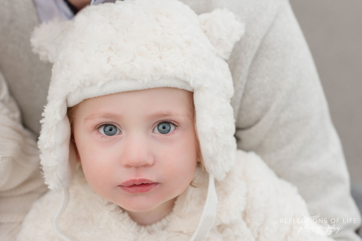 Little girl in adorable white hat in winter