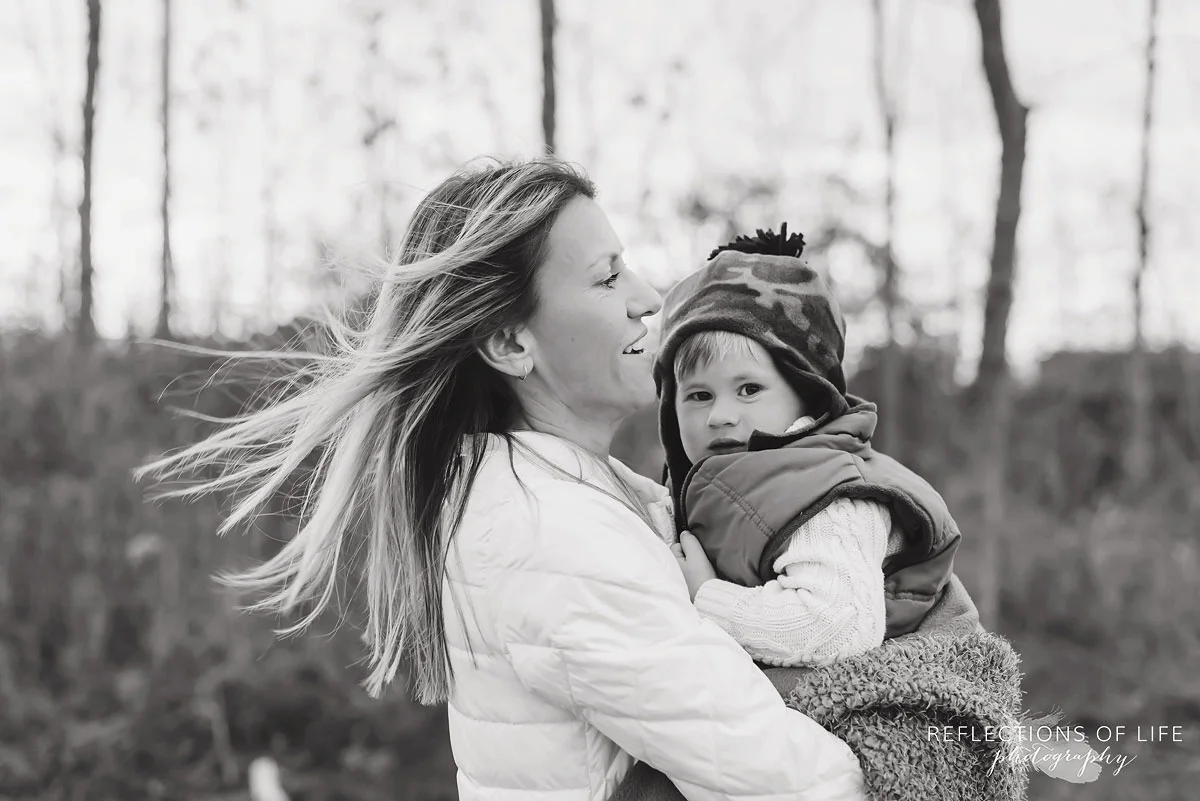 Moms hair blowing in the wind while holding her son