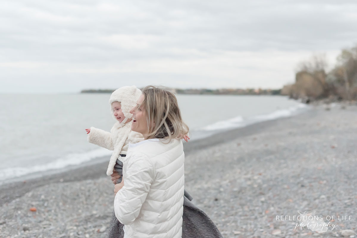 Mom laughing with her little girl on the beach in winter