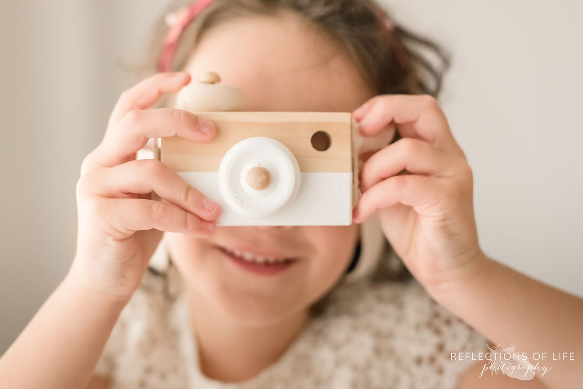young girl holding toy camera