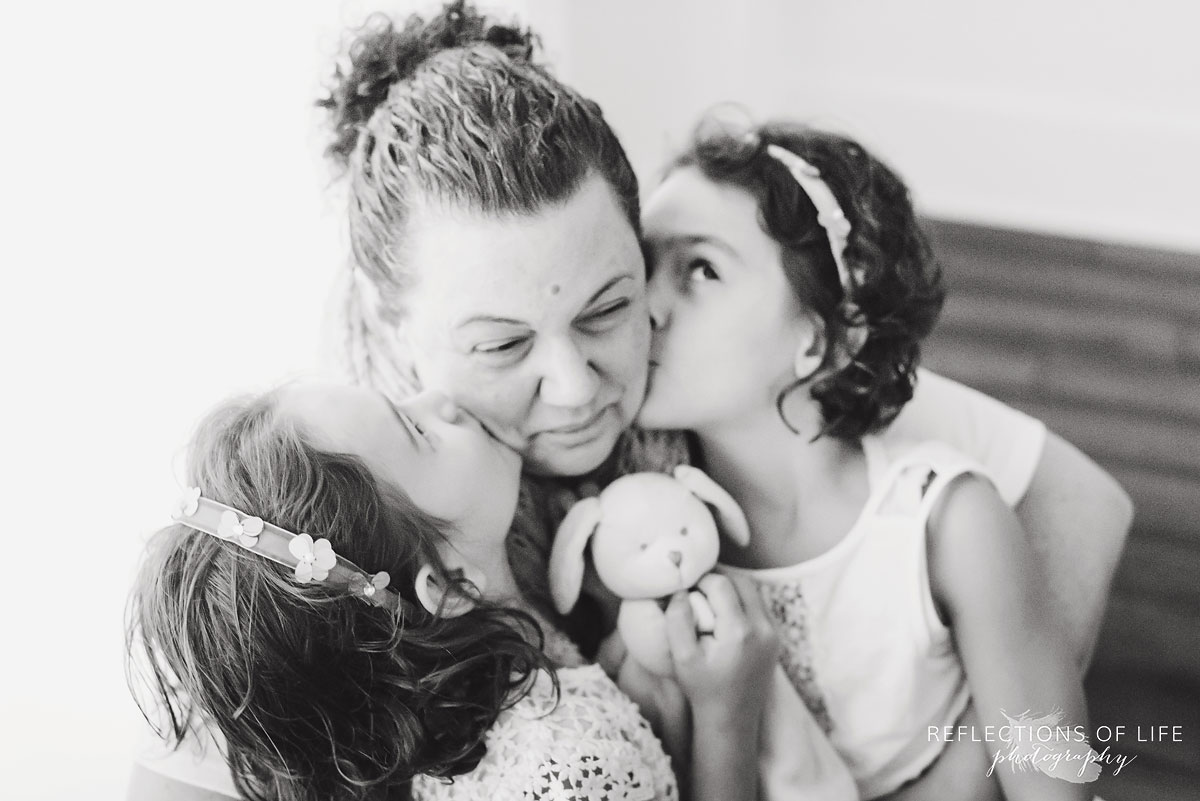 twin sisters kissing mother on the cheeks black and white