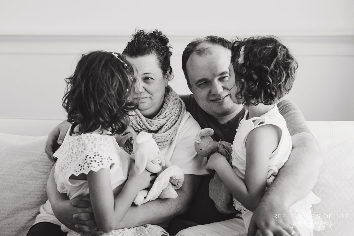 twin girls sitting on parents laps black and white