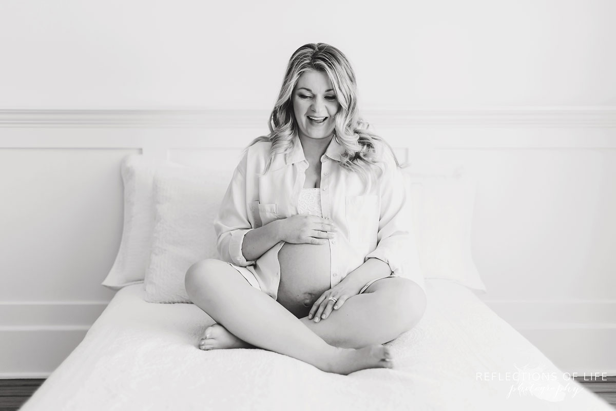 black and white pregnant woman sitting on bed