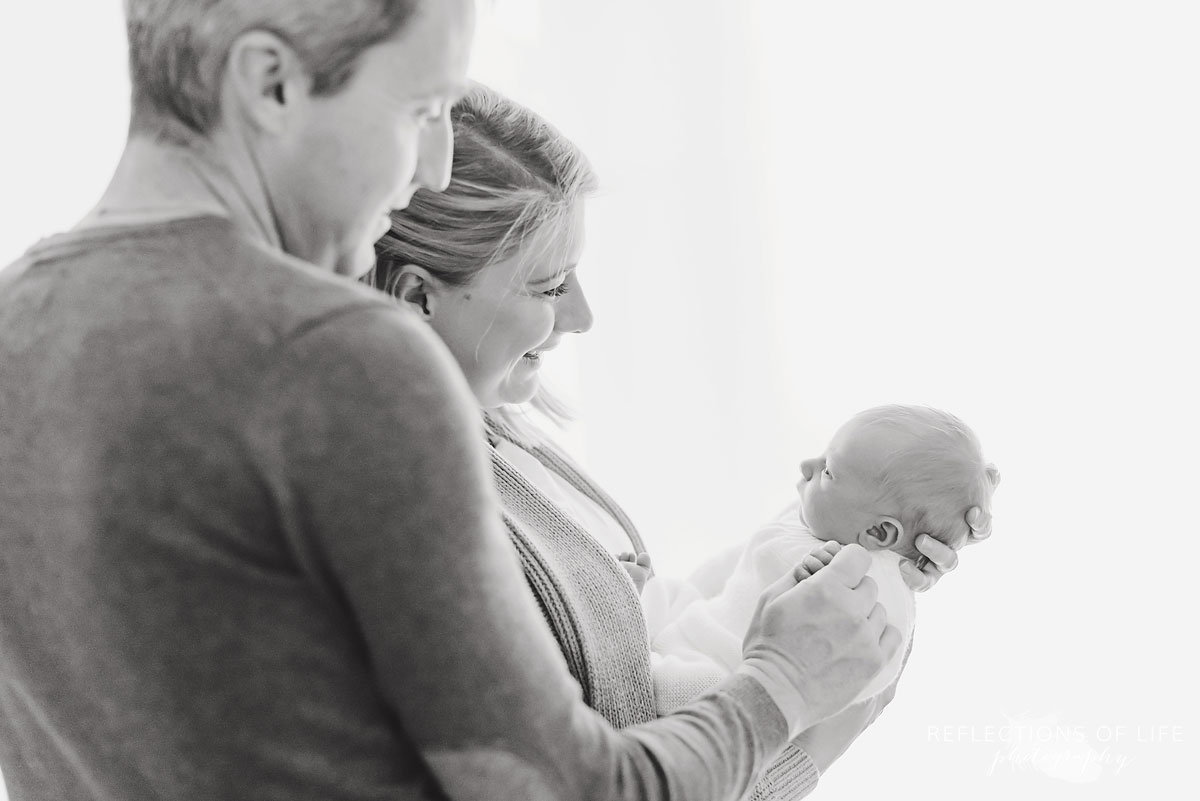 mother and father smiling at newborn child black and white