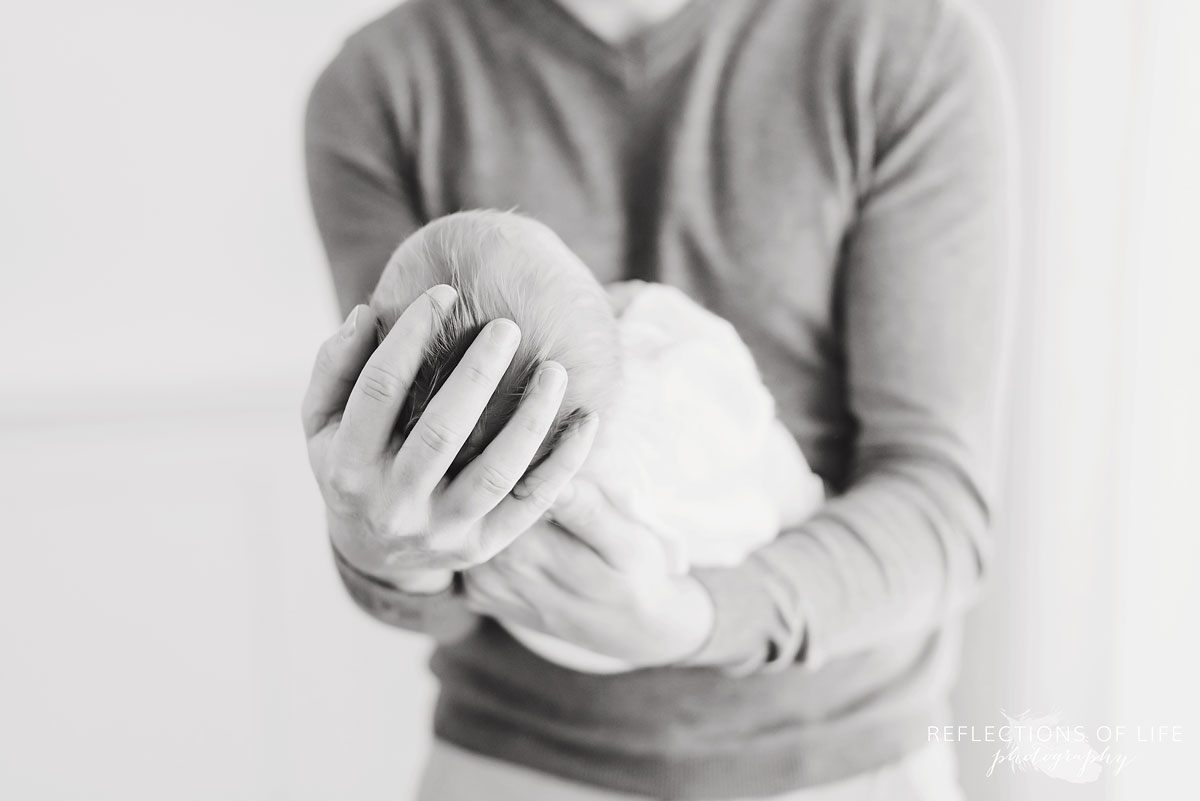 father holding newborn child in hands black and white