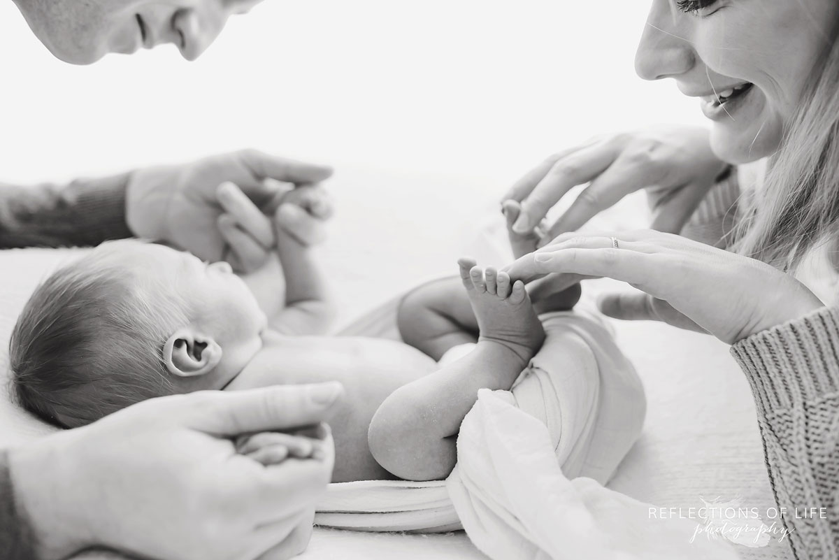 mother and father playing with newborn black and white
