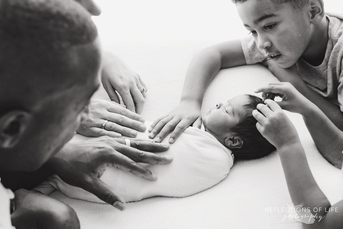 family with hands on newborn child black and white