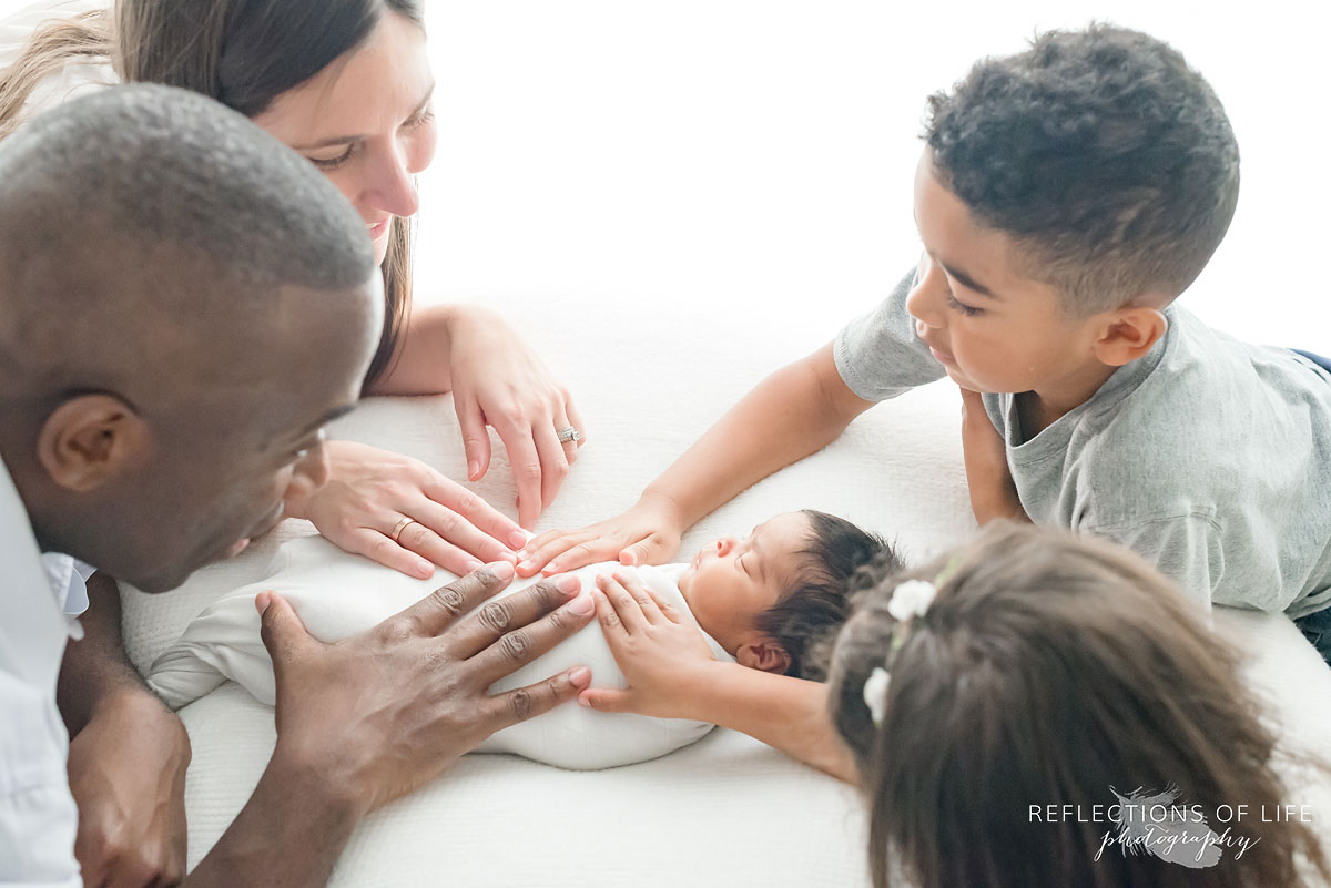 family with hands on newborn baby