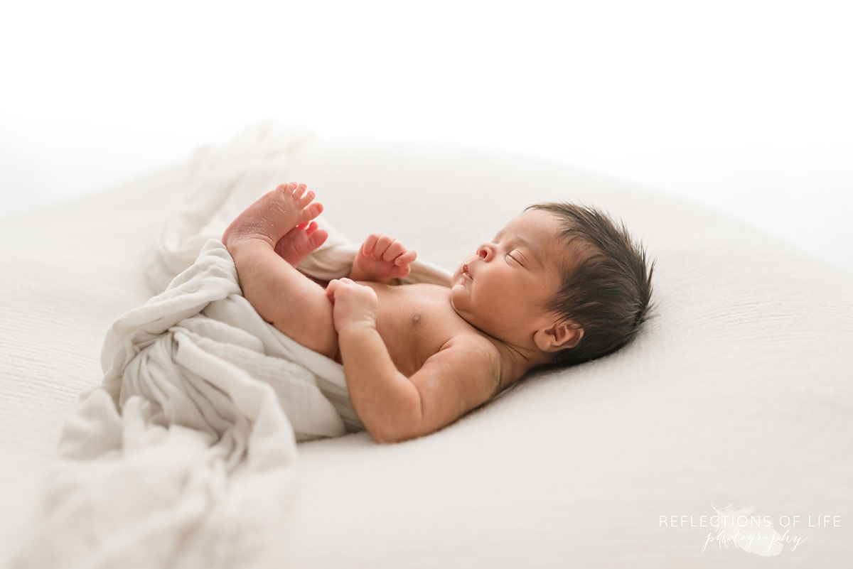 newborn laying on back with blanket