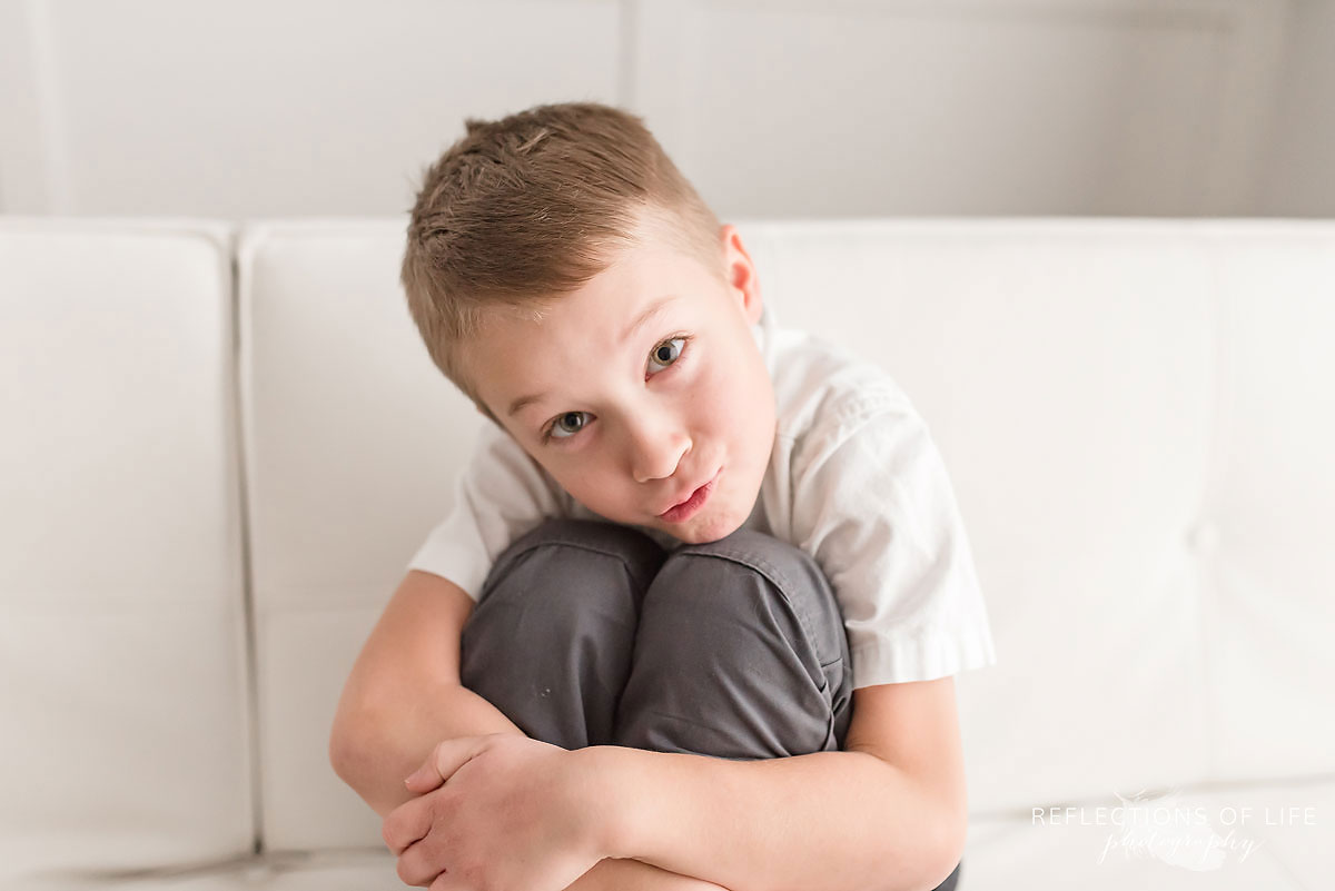 young boy sitting down hugging his knees.jpg