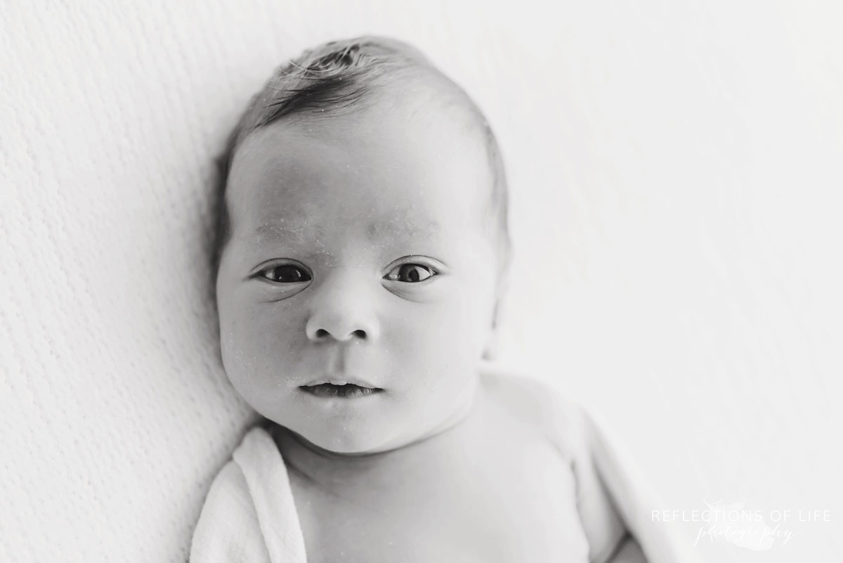 Young baby boy looking into camera black and white