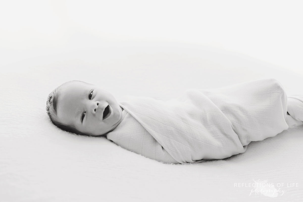 happy young baby boy newborn looking into camera black and white