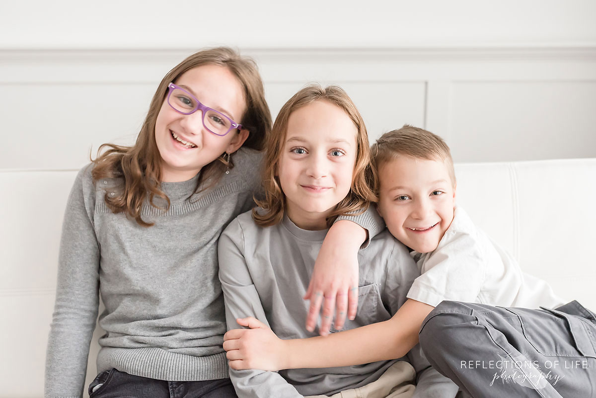 three happy smiling siblings sitting beside eachother on couch.jpg