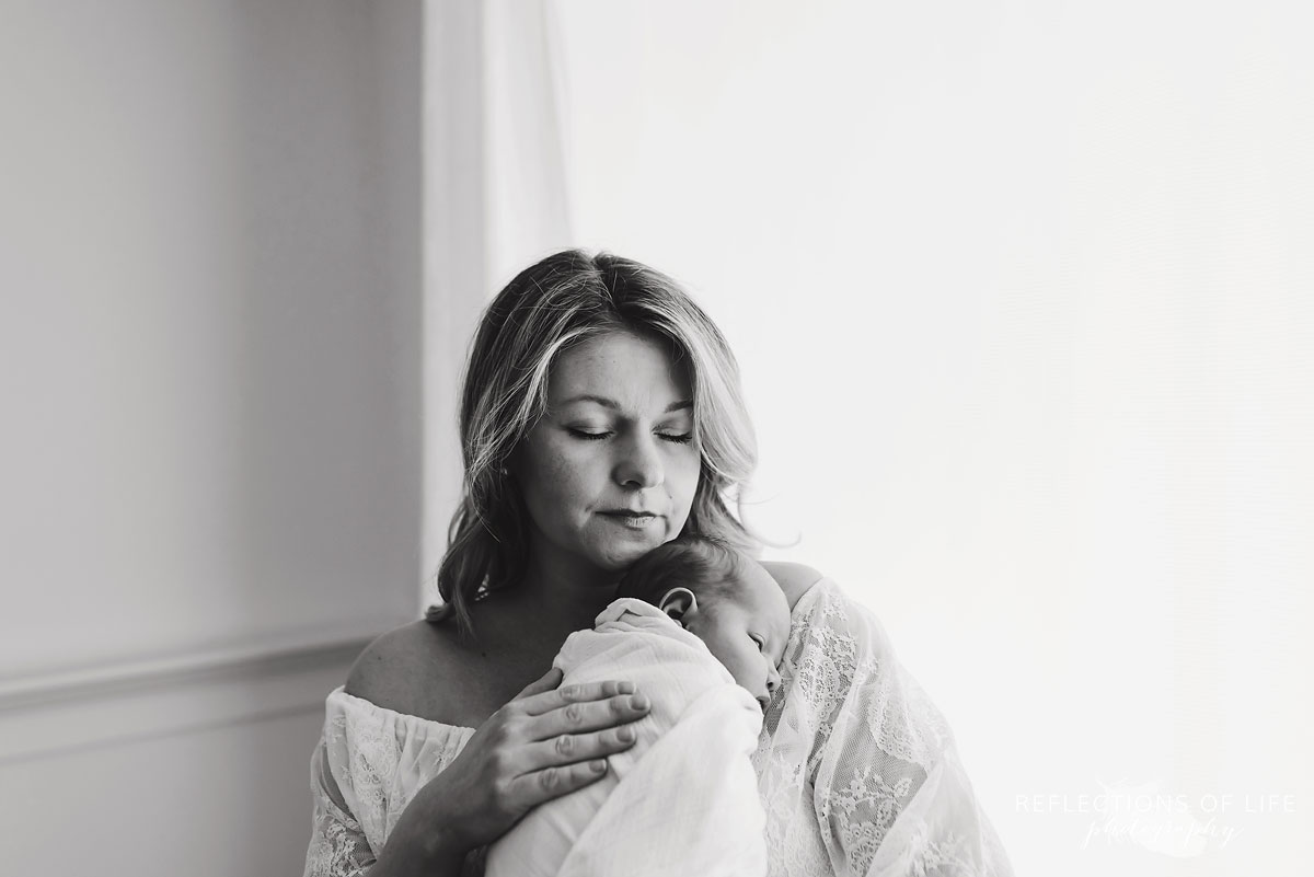 mother holding newborn baby in her arms black and white
