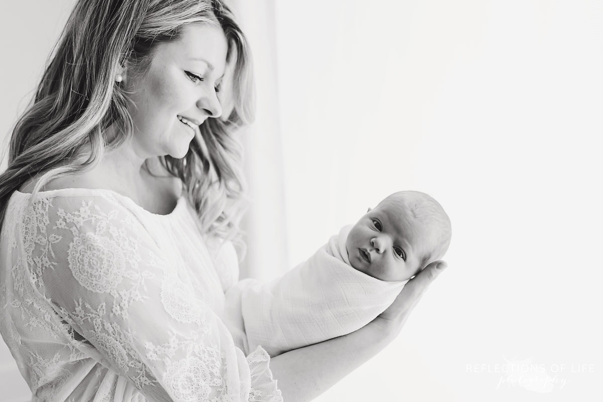 mother holding newborn baby girl in arms black and white