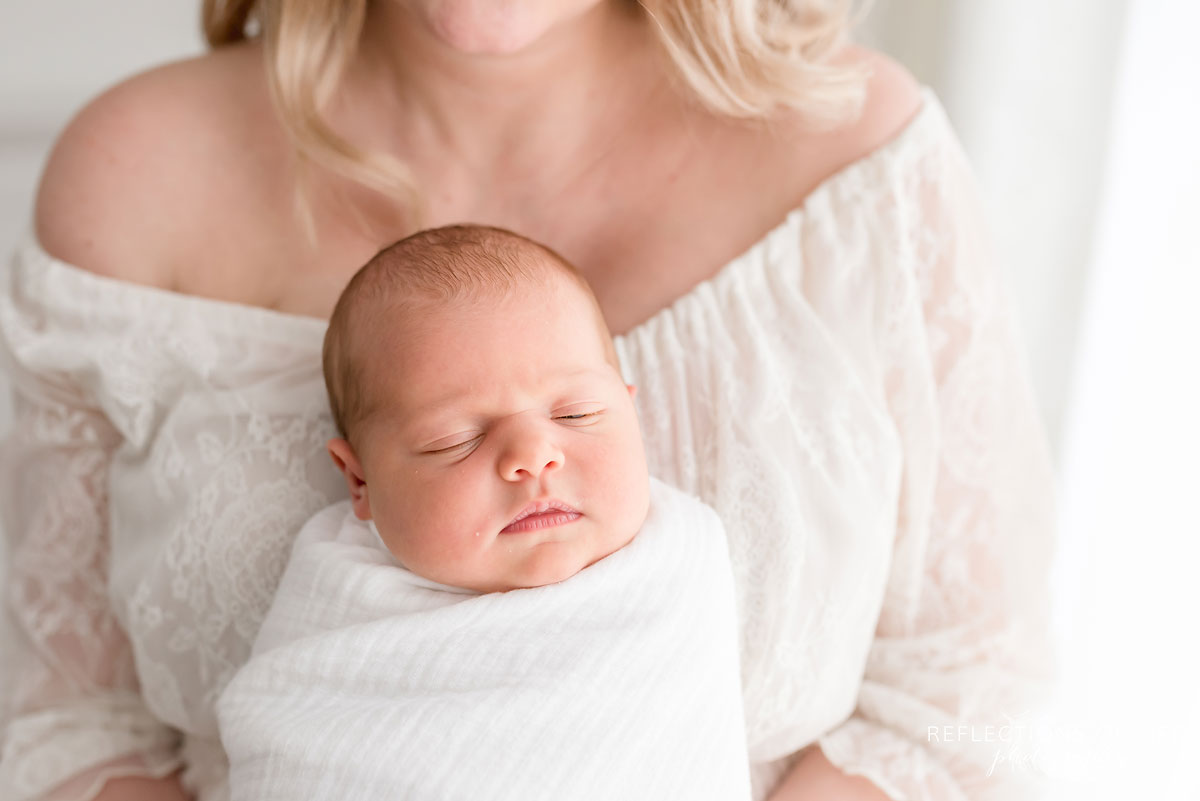 newborn baby girl sitting in mothers lap