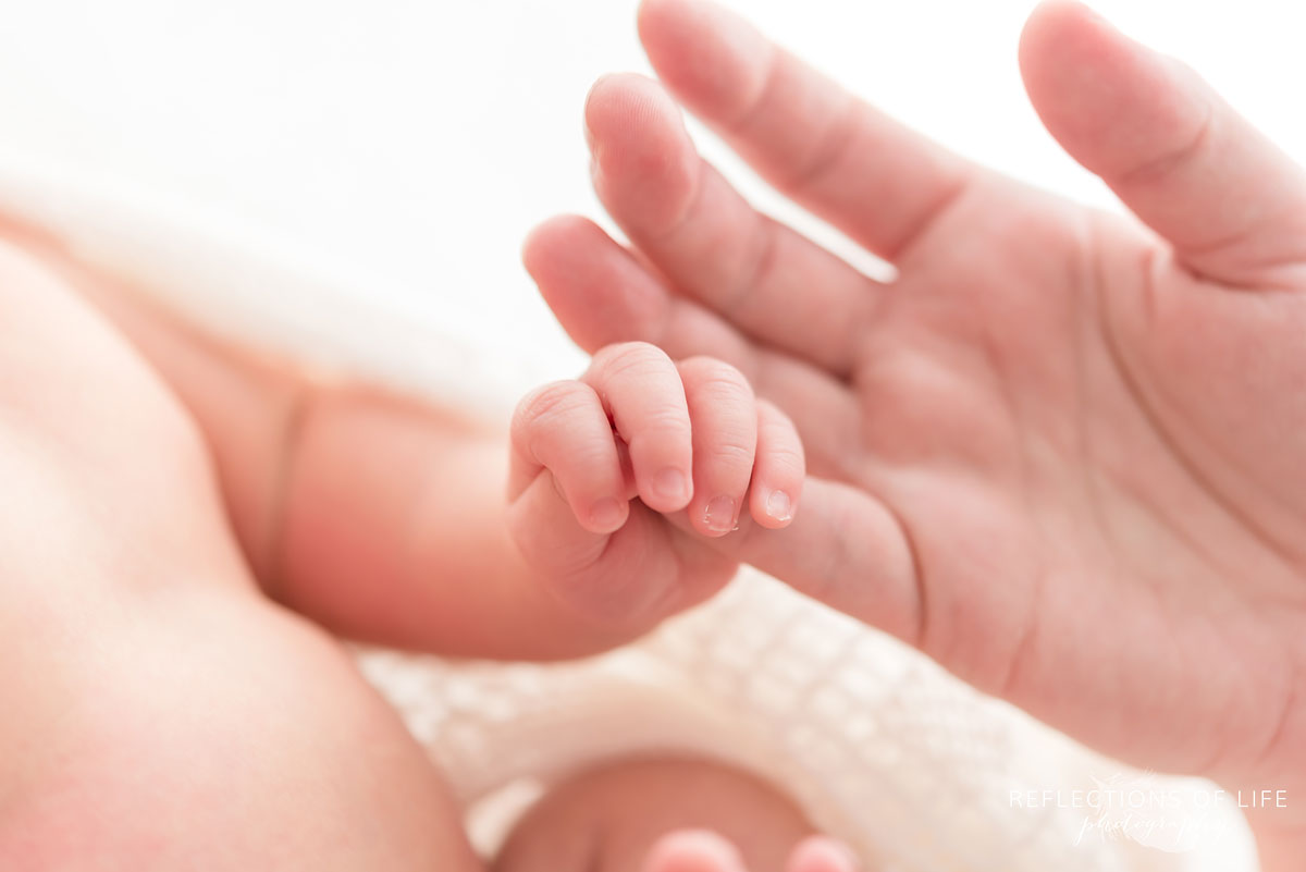 newborn baby holding mother finger