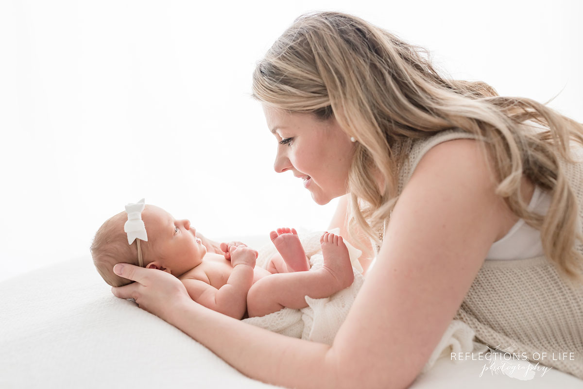 mother laying down looking at newborn daughter