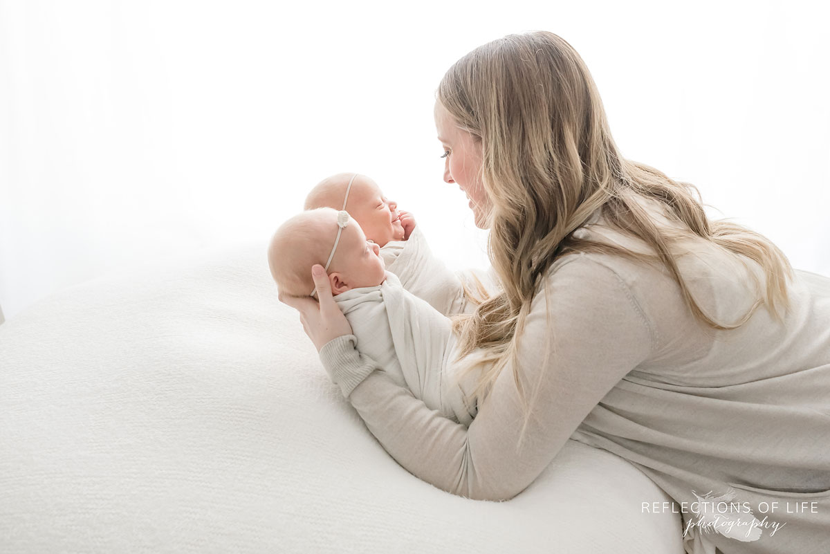 mother smiling at twin newborns