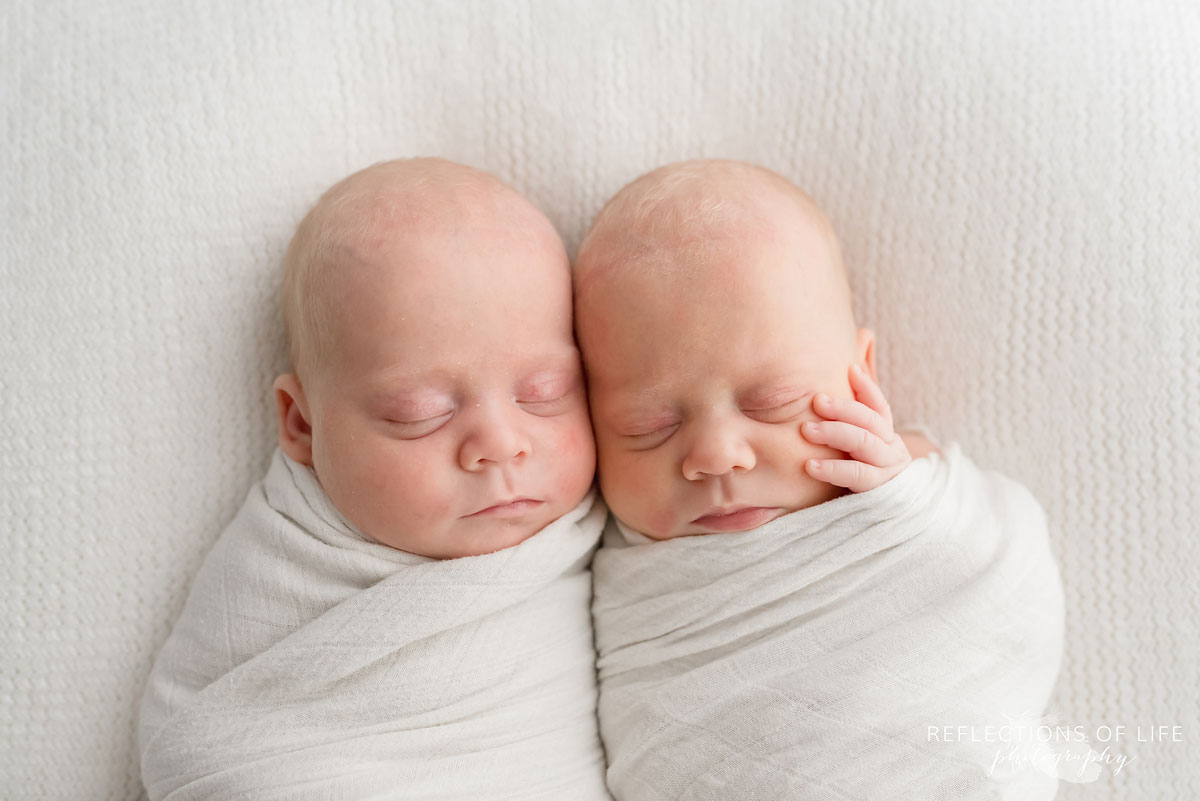 newborn baby girls laying together on bed