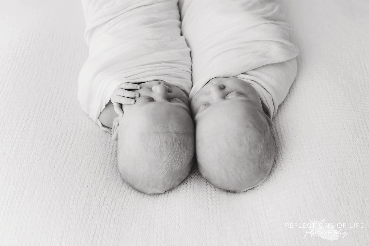 newborn baby girls laying together on bed black and white