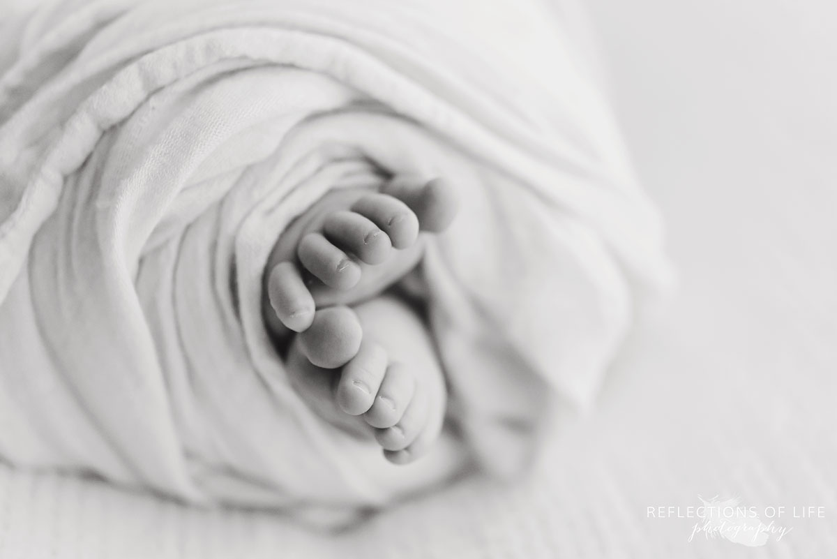 newborn baby girl wrapped up feet black and white