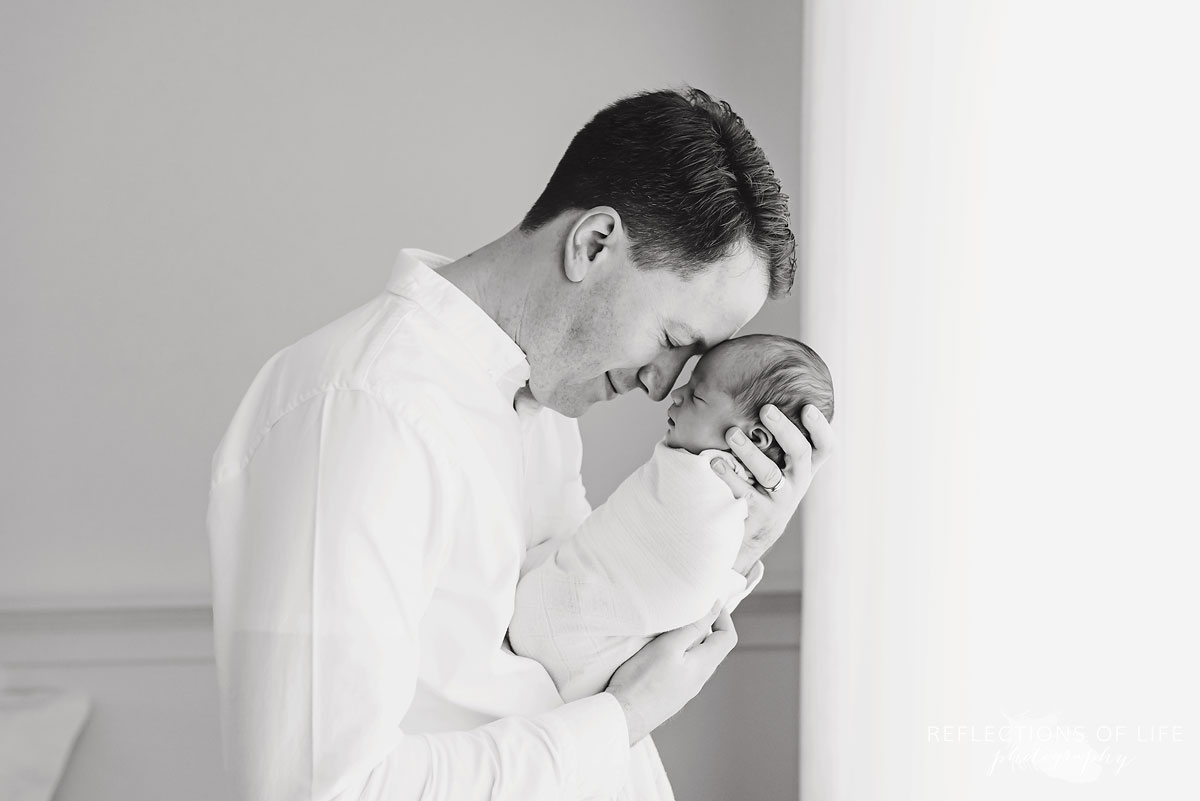 proud daddy resting his head on his gorgeous newborn baby girl