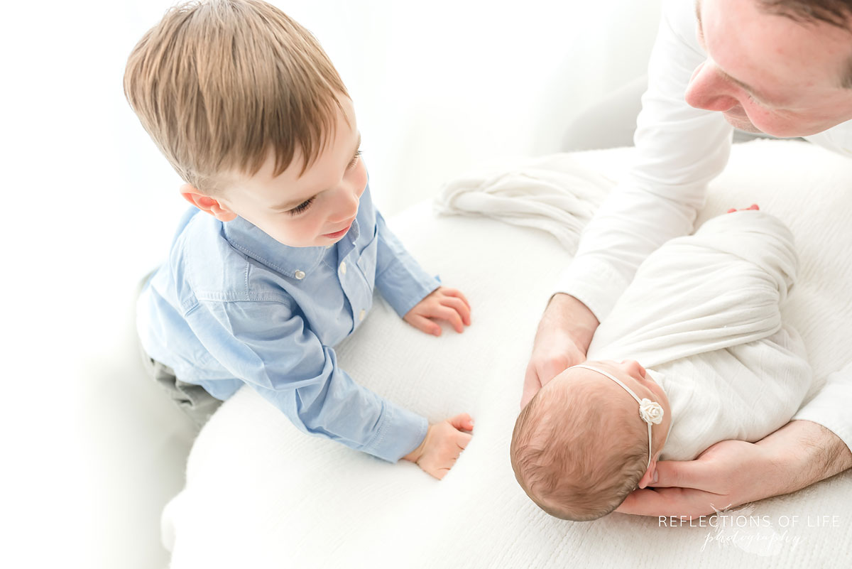 big brother looks down at his brand new baby sister in love