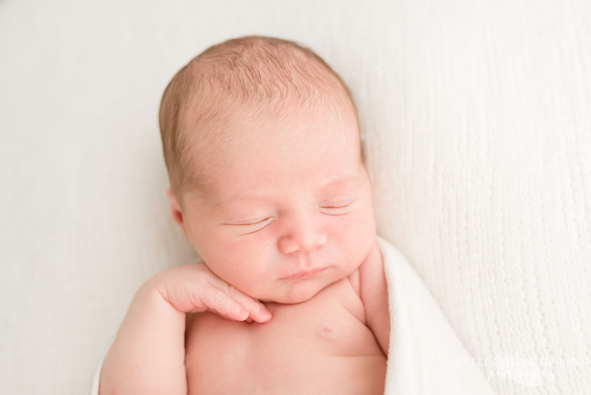 close up image of newborn baby girl in all white studio grimsby ontario