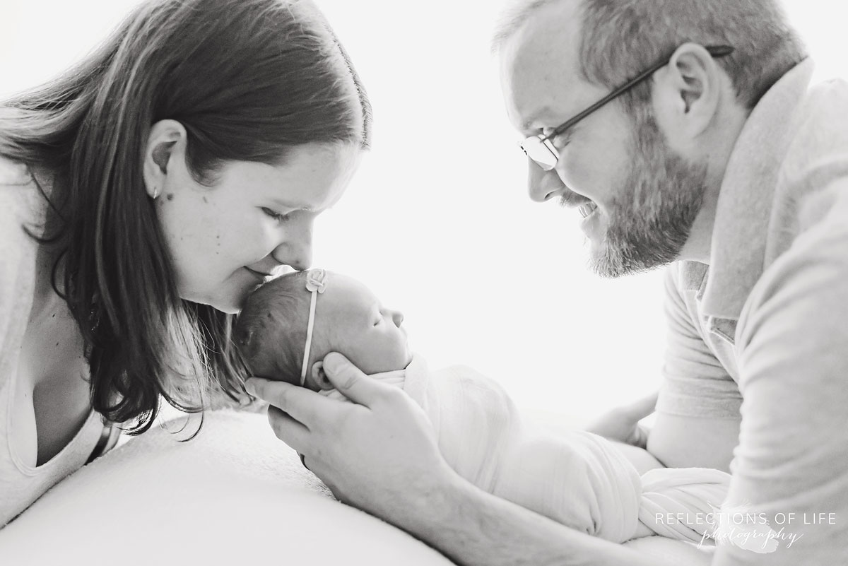 newborn baby girl with proud mom and dad backlit in studio