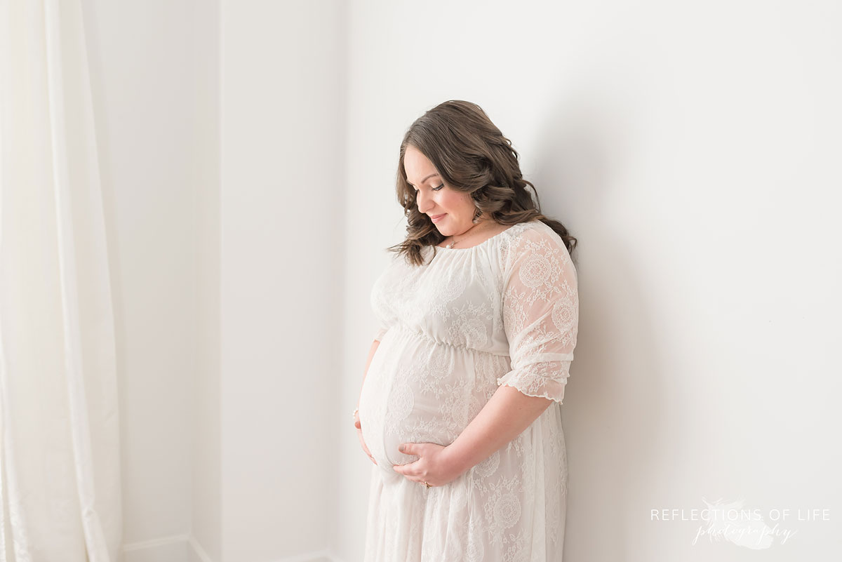 Gorgeous mom in white lace dress natural light studio maternity photo
