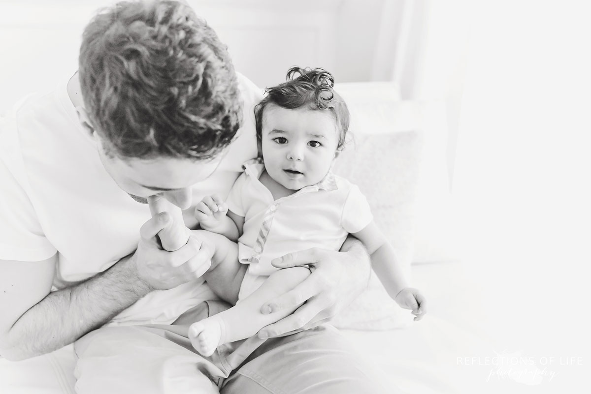 daddy kissing baby's toes in black and white