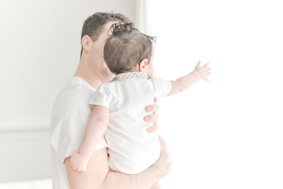 daddy showing baby white curtains in professional photo studio niagara ontario