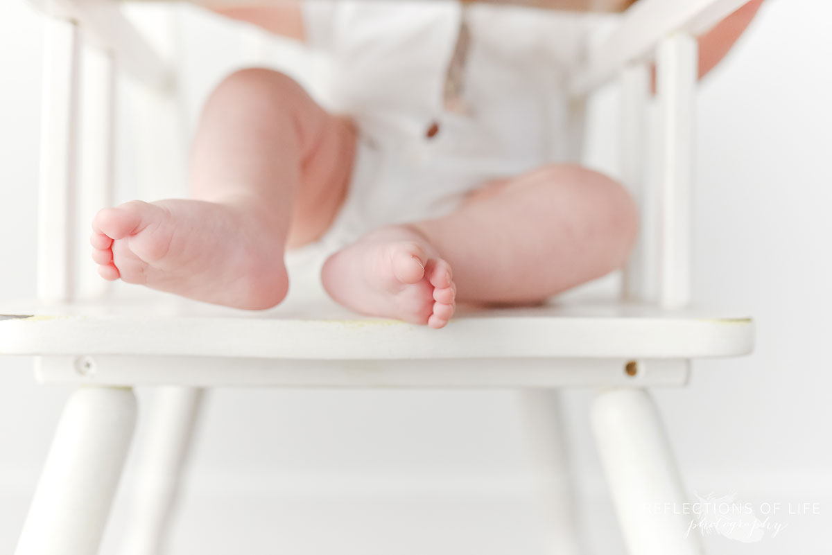 baby boy toes image while sitting in a white antique high chair