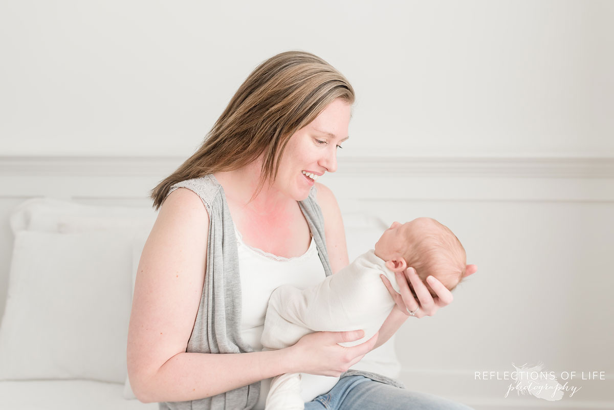 colour portrait of mom smiling at newborn baby