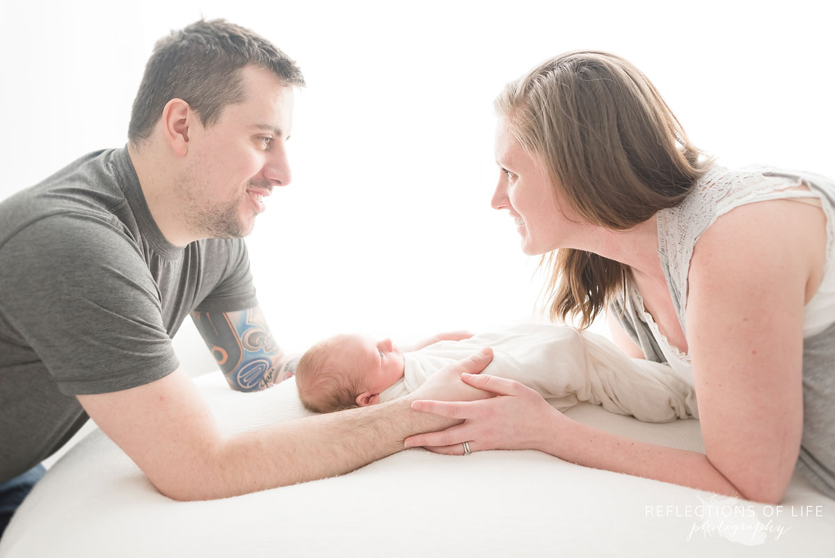 mom and dad with their hands on newborn baby boy