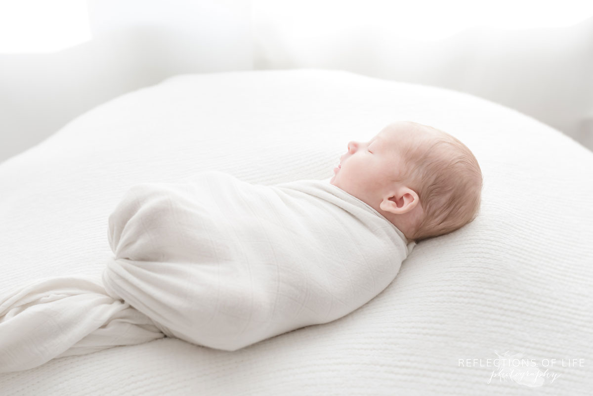 newbrn baby boy swaddled in white