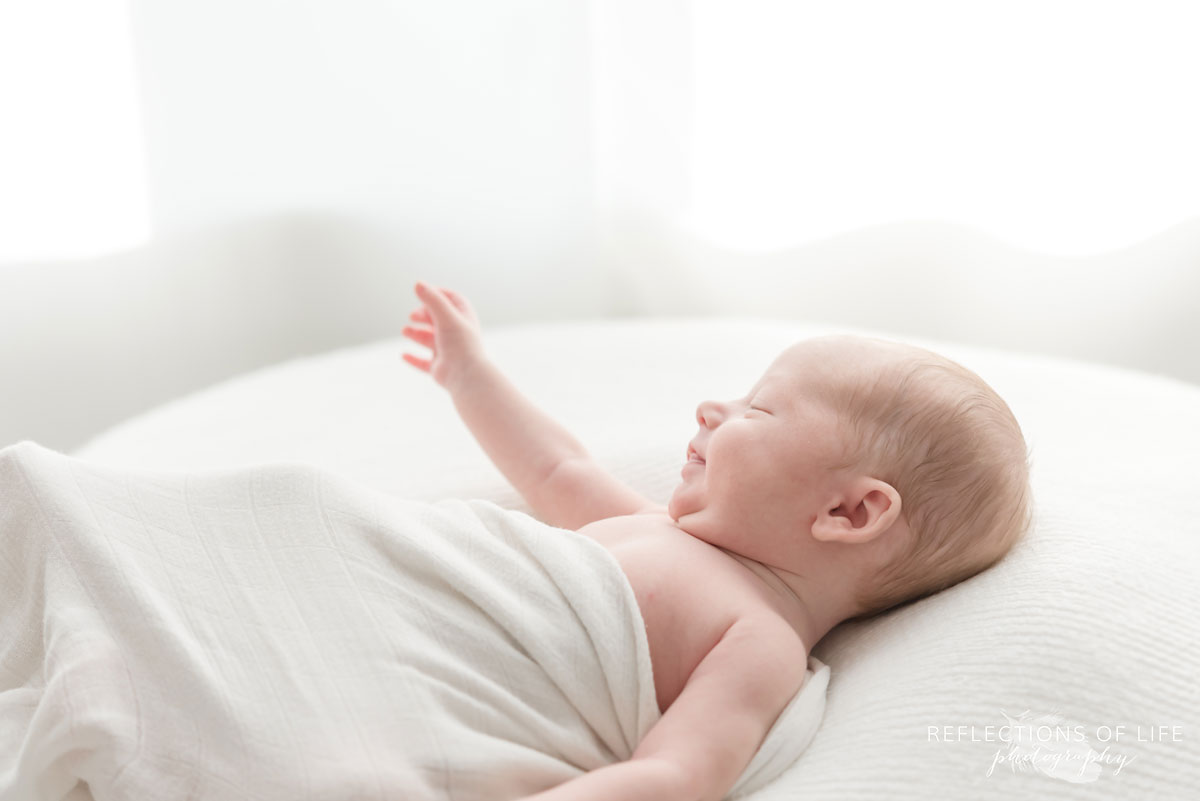 newborn smling with arm in the air