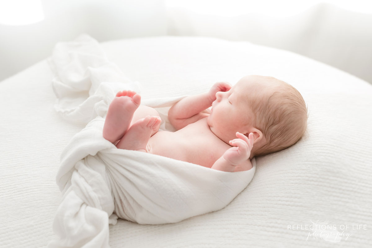 baby boy asleep swaddled in white