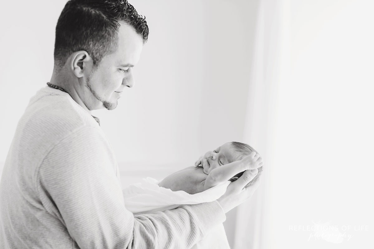 Newborn in her daddy's arms in Grimsby Ontario white studio