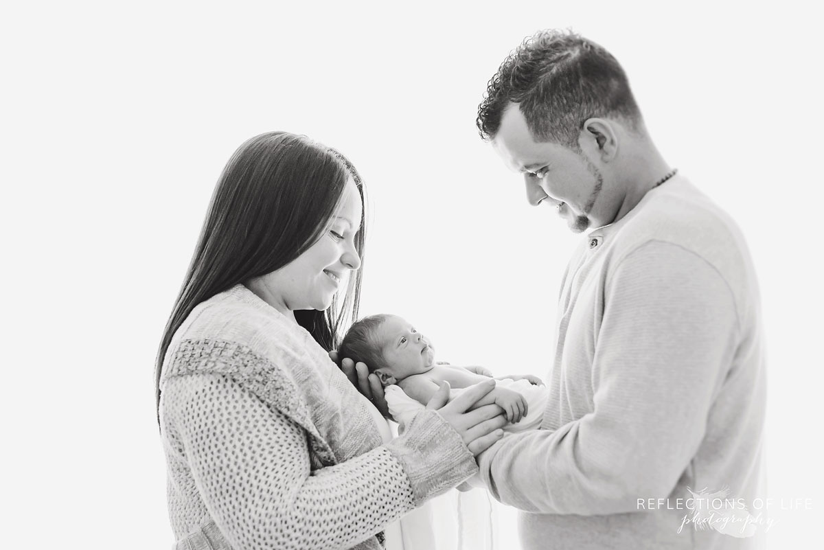 Newborn in the arms of her parents in black and white