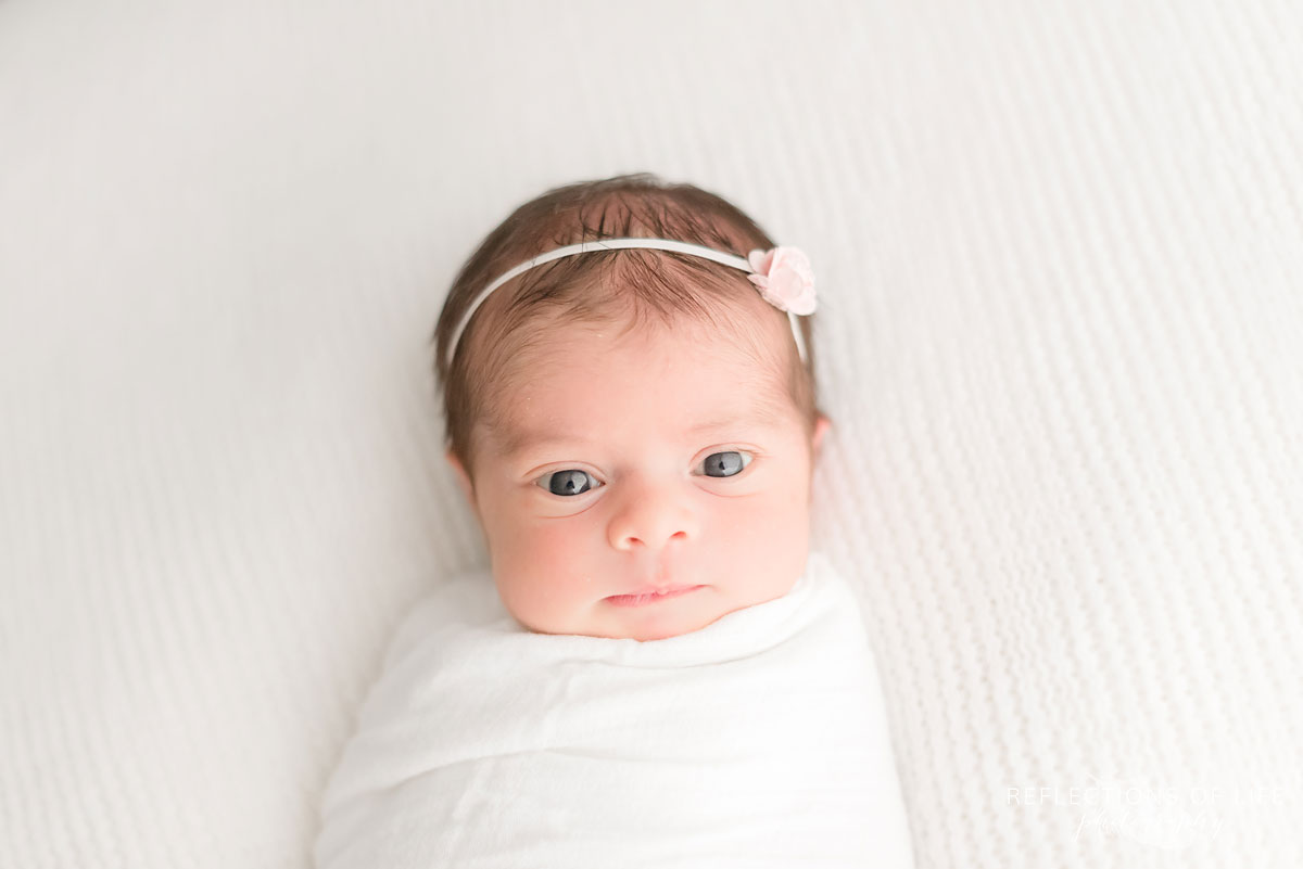Newborn baby girl looking straight into the camera