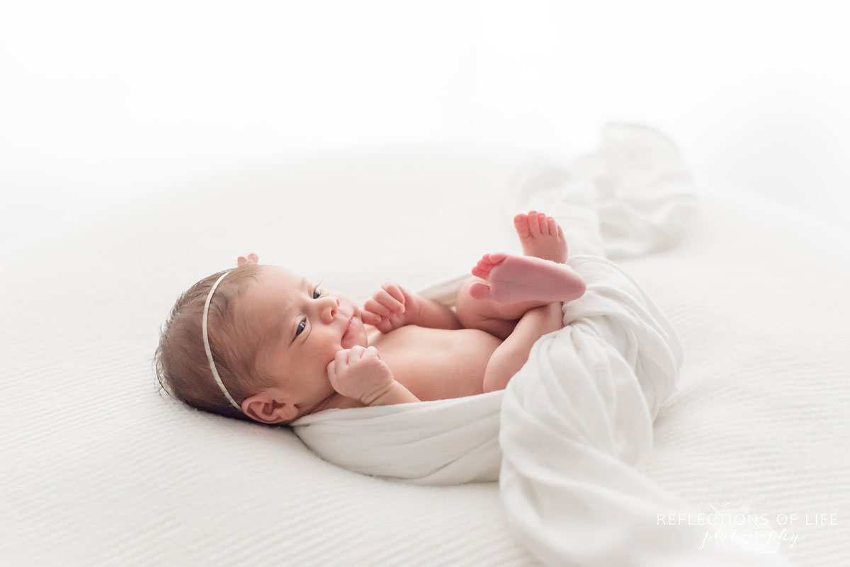 Baby girl wrapped in white on white beanbag