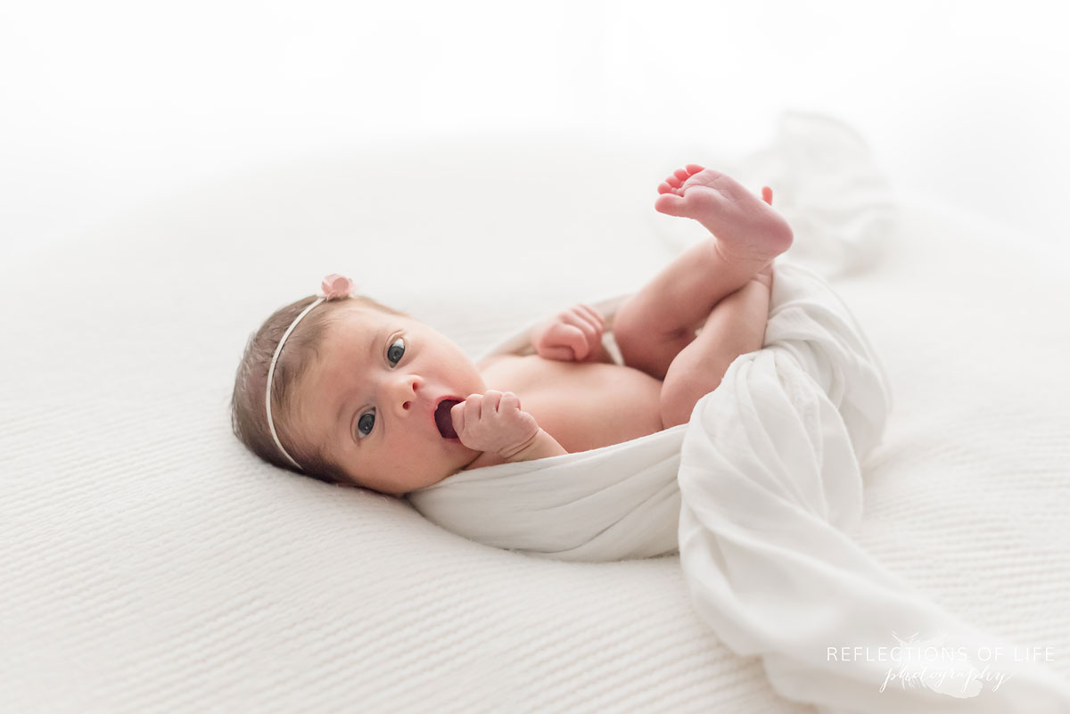 Funny expression from newborn baby girl laying on beanbag during photoshoot